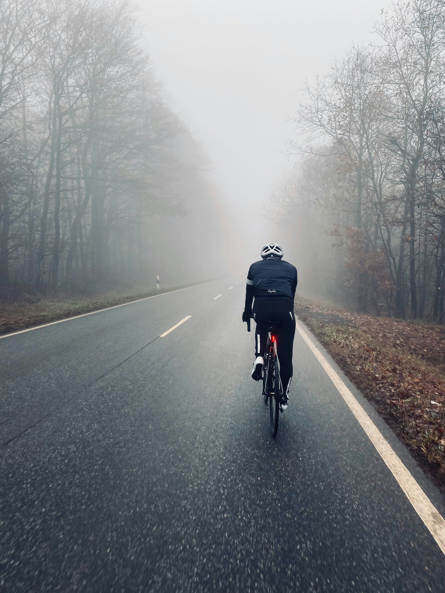 Rennradfahrer auf einer leeren Landstraße im Winterlicht