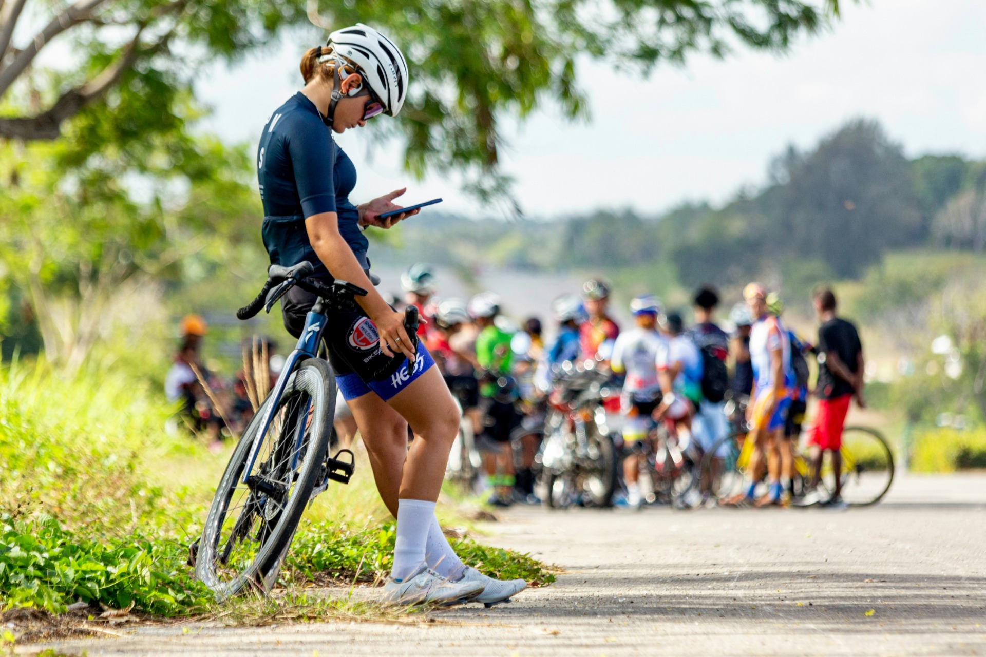 Radrennfahrerin mit Helm schaut sich ihre Leistungsdaten auf dem Smartphone an.