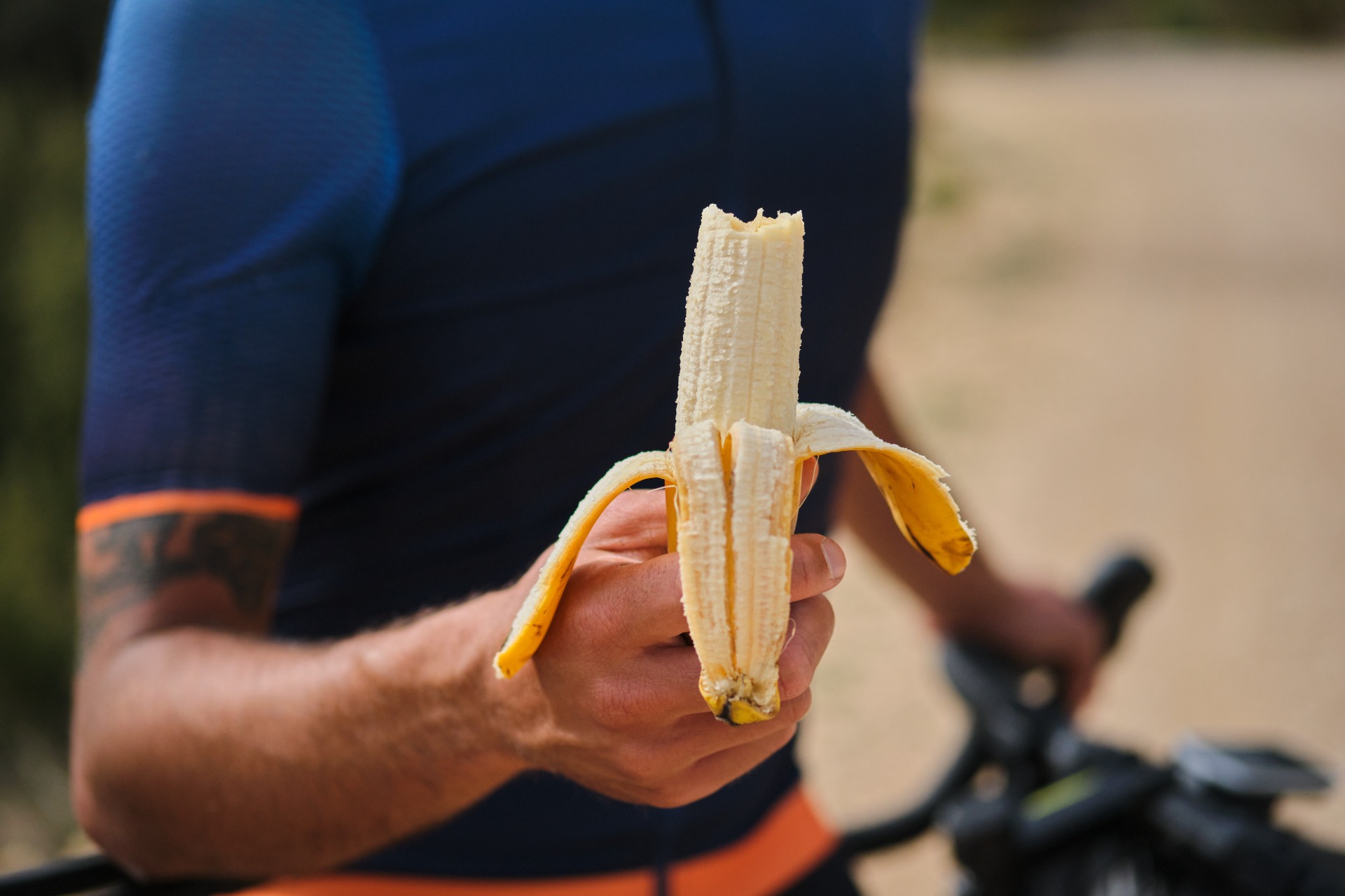 Radfahrer hält eine aufgeschnittene Banane mit gelber Schale.