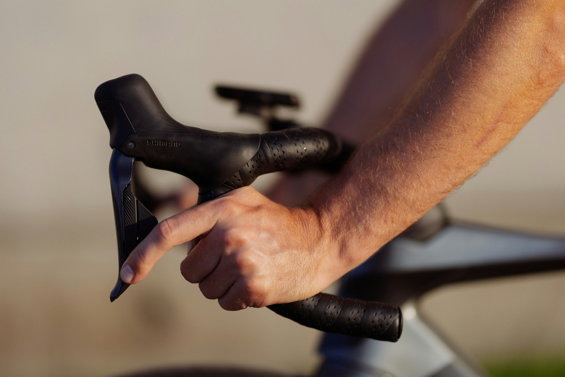 Hände halten einen schwarzen Fahrradbremshebel mit Griffpolster.